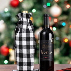 Christmas buffalo plaid wine gift bag with drawstring on a bottle against holiday lights