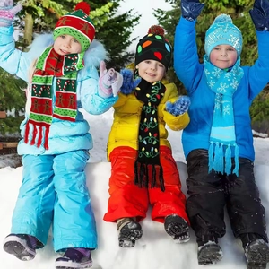 Kids wearing colorful knitted Christmas hat and scarf sets in a winter forest snowy scene