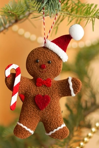 Detail of gingerbread man felt ornament with red hat on Christmas tree branch