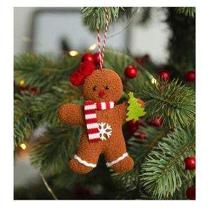 Three gingerbread man plush ornaments hanging on a festive Christmas tree with warm lights