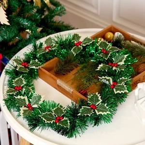Kerstkrans van klatergoud met rode bessen en hulstblaadjes op een houten dienblad
