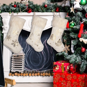 3er-Set beige Weihnachtsstrümpfe mit goldener Prägung und weißem Plüsch am Kamin aufgehängt