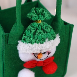 Close-up of 3D snowman detail on green felt Christmas gift bag with knit hat and bow