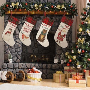 Set of four festive Christmas stockings hanging on a stone fireplace mantle with holiday decor