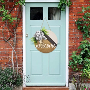 Panneau de bienvenue en bois avec eucalyptus et nœud à carreaux sur une porte bleue
