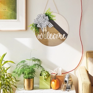 Détail d'un panneau de bienvenue en bois avec feuilles d'eucalyptus et perles rustiques