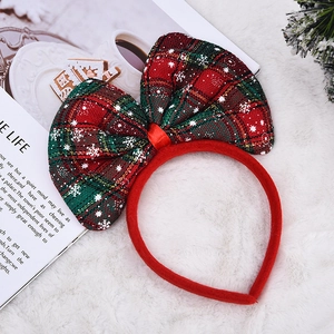 Detail eines Weihnachts-Haarreifens mit rot-grüner Karo-Schleife und Schneeflocken