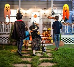 Close-up of hanging LED ghost lights on a festive Halloween porch with pumpkins