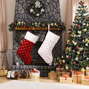 Quilted red and white Christmas stockings with faux fur trim hanging by fireplace