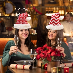 Detail of red knit Santa hat with white snowflake patterns and plush trim in festive setting