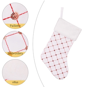 Macro detail of red grid embroidery with gold sequins on white plush Christmas stockings