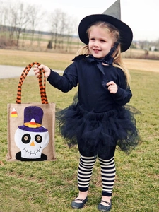 Linen Halloween tote bag with skull patch and striped handles shown on green grass