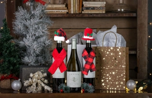 Close-up of festive Christmas wine bottle covers with sequin hats and plaid scarves