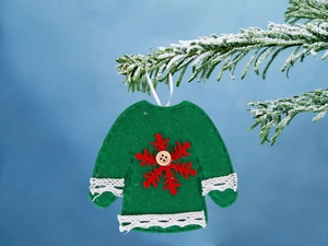 Dettaglio maglione natalizio in feltro verde con fiocco di neve su un ramo innevato