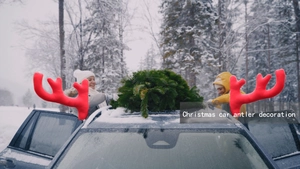 Close-up of red plush car antlers attached to a window in a snowy winter forest setting