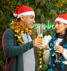 Close-up of festive guests wearing red Santa hats with gold and blue tinsel garlands