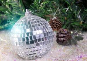 Silver disco mirror ball ornament with hanging ring on snowy Christmas tree branches