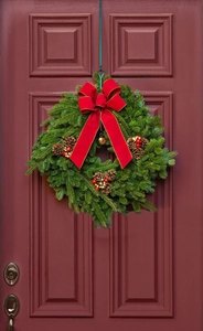 Close-up of a Christmas wreath with pine needles, red velvet bow and gold bell detail