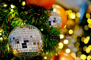 Macro detail of silver mirror disco ball showing reflective glass tiles and warm bokeh light