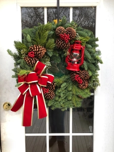 Close-up of a Christmas wreath with pine cones, red berries, and a vintage red lantern