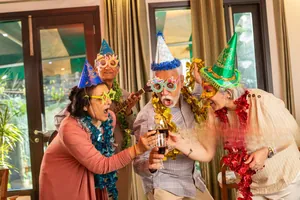 Joyful elderly group celebrating with colorful party hats, glasses and shiny tinsel garlands