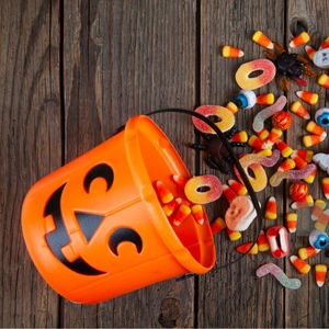 Classic orange Halloween pumpkin candy bucket overflowing with colorful candy corn and sweets