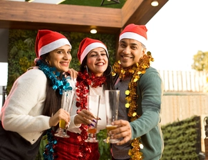 Three festive Christmas hats paired with shiny colorful metallic tinsel garlands for parties