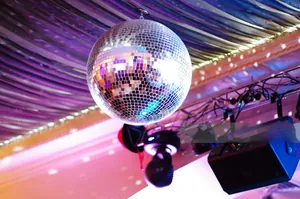 Close-up of a glittering mirror disco ball with a metal hook hanging in a party venue