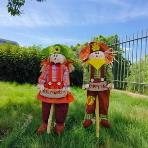 Detail of harvest scarecrows with Give Thanks signs and wooden sticks for garden decor