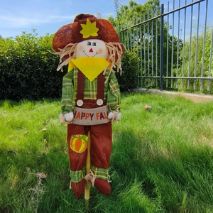 Garden scarecrow decor with HAPPY FALL banner and wooden stake on sunny lawn