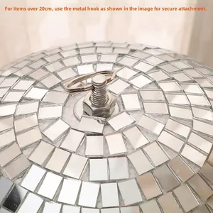 Detailed close-up of a large disco ball featuring a reinforced metal hook and glass tiles