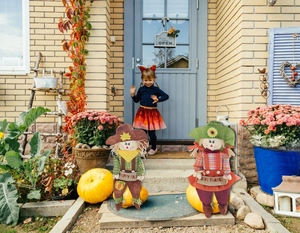 Detail view of harvest scarecrow couple with Happy Fall and Give Thanks signs on pumpkins