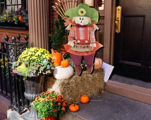 Detail of harvest scarecrow doll holding Give Thanks sign for Thanksgiving porch decor