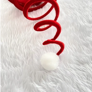 Detailed close-up of a red spiral spring Christmas hat with a soft white plush pom-pom