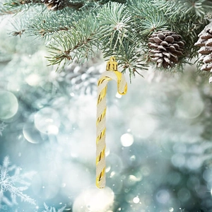 Detail of a 13cm gold and white candy cane ornament hanging on a snowy Christmas tree branch