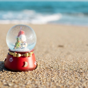 Christmas snowman glass snow globe with red base on a sandy beach setting