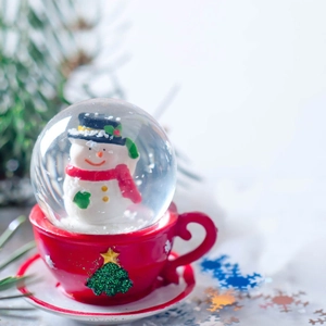 Christmas snowman snow globe featuring a red coffee cup base and festive pine tree motif
