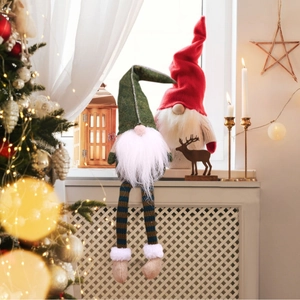 Set of two long-legged Christmas gnomes with green and red hats on a festive windowsill
