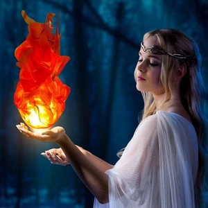 Close-up of glowing orange floating fireball prop used for magical forest cosplay photography