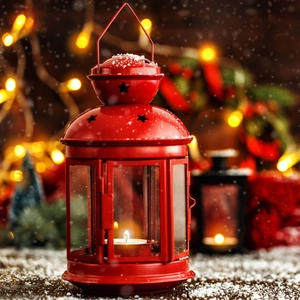 Close-up of a red vintage metal lantern with star cutouts and a lit candle inside