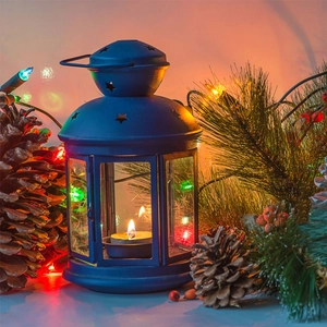 Close-up of a blue star-cut lantern with a lit candle and festive Christmas pinecone decor