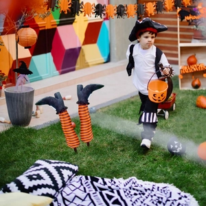 Outdoor Halloween yard stakes featuring striped witch legs and black pointed boots on lawn