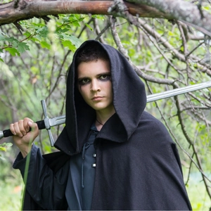 Medieval black hooded cloak for Halloween cosplay in mystical forest setting with sword