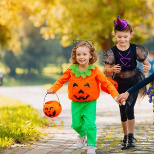 Kids Halloween outfits featuring pumpkin costume and black witch dress with spider web print