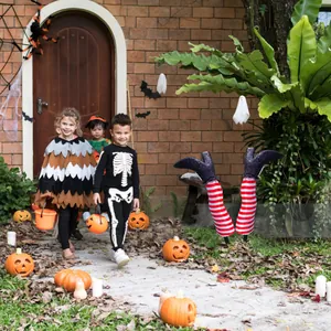 Detailed view of red and white striped witch legs with glitter boots in a spooky garden