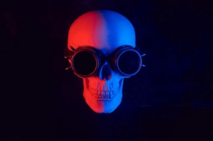 Front view of realistic skull prop wearing spiked steampunk goggles with red and blue lighting