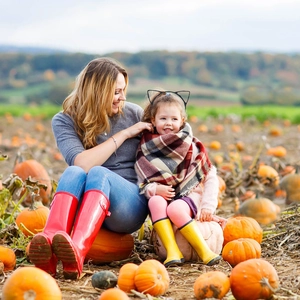Detail showing a minimalist black cat ear headband on a child in a pumpkin field setting