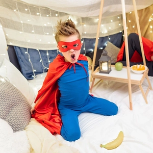 Detailed view of children's superhero costume with red cape and blue jumpsuit
