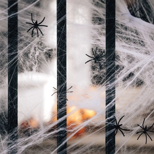 Macro shot of stretchable white spider web with black plastic spiders on a metal fence