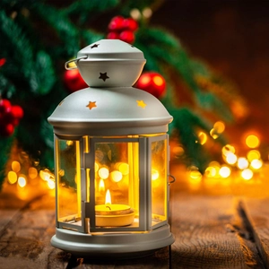 Close-up of white metal vintage star lantern with lit candle and warm festive bokeh